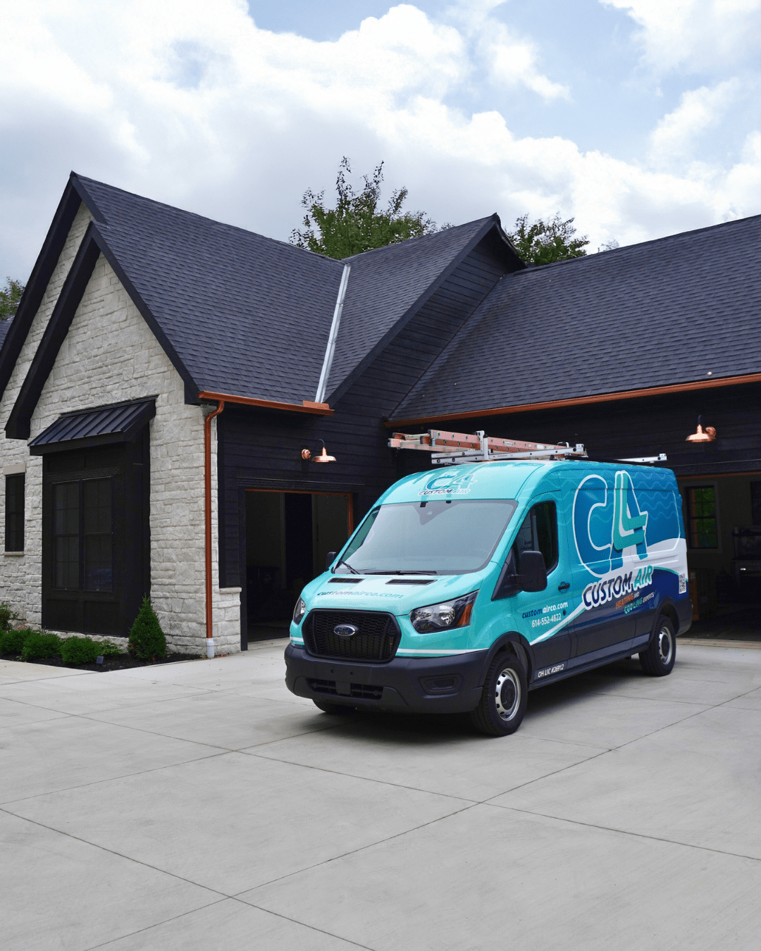 Custom Air HVAC service van parked in the driveway of a modern home with dark siding, stone facade, and open garage.