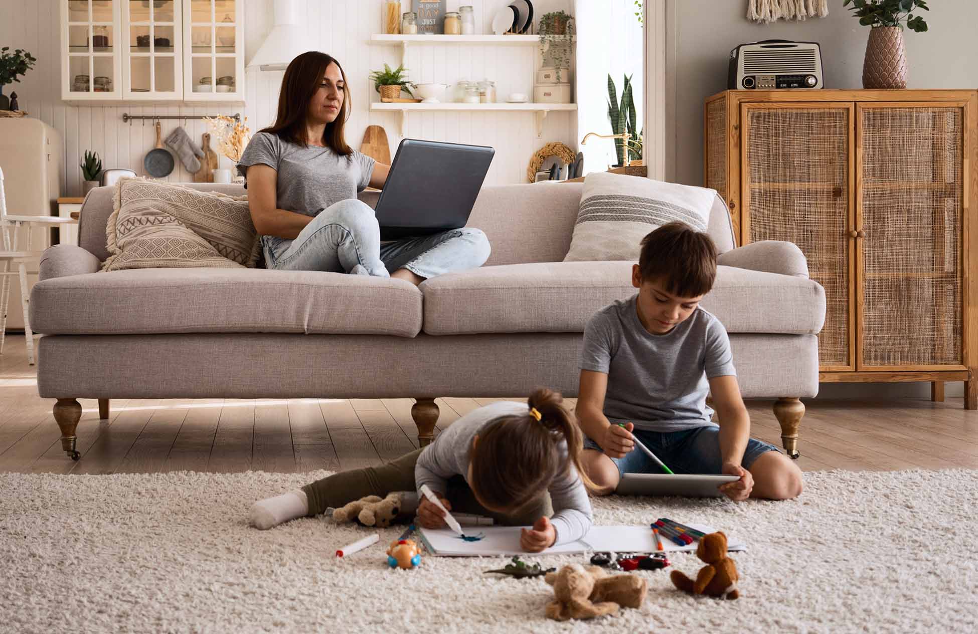 Woman working on laptop while kids are playing