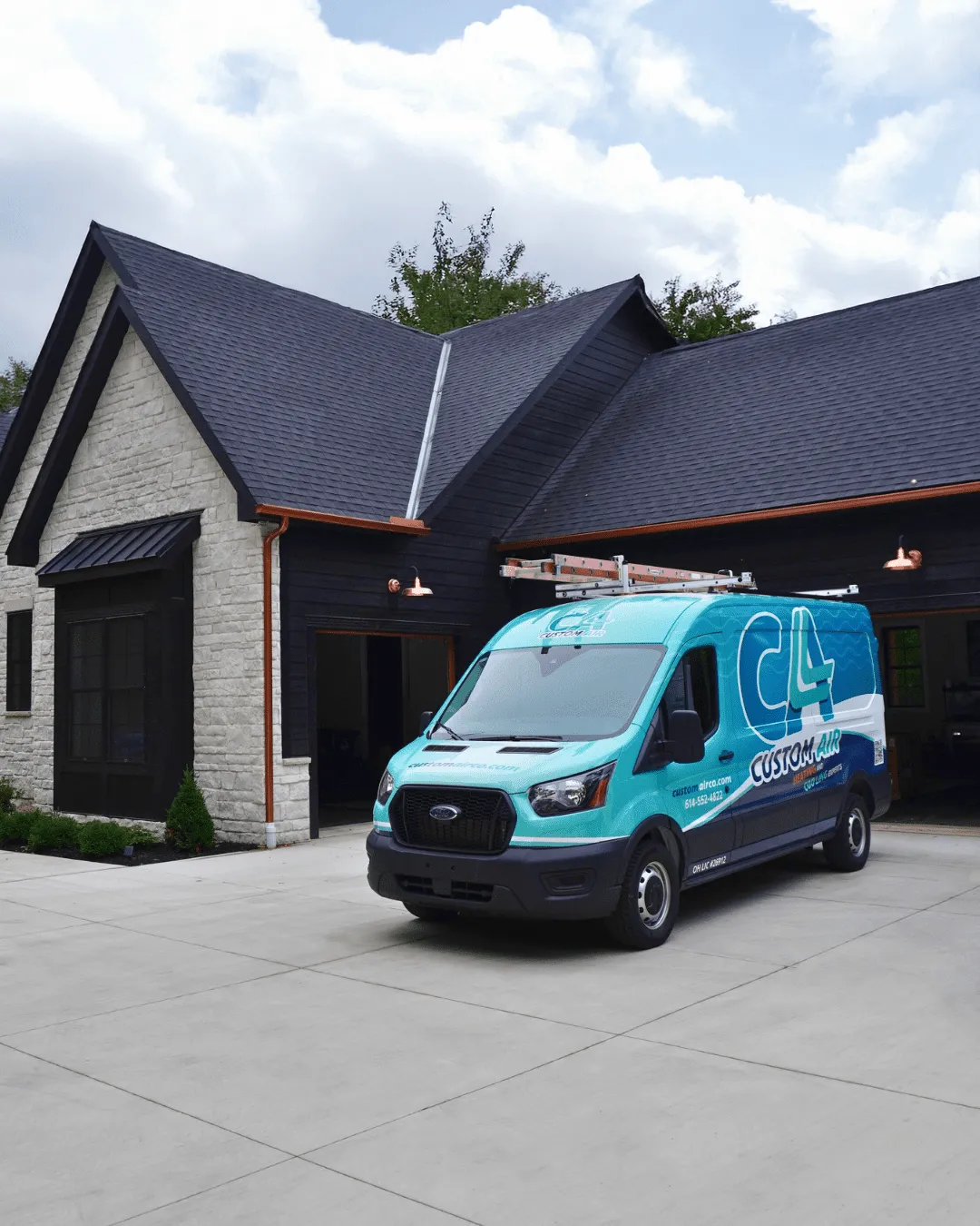Custom Air HVAC service van parked in the driveway of a modern home with dark siding, stone facade, and open garage.